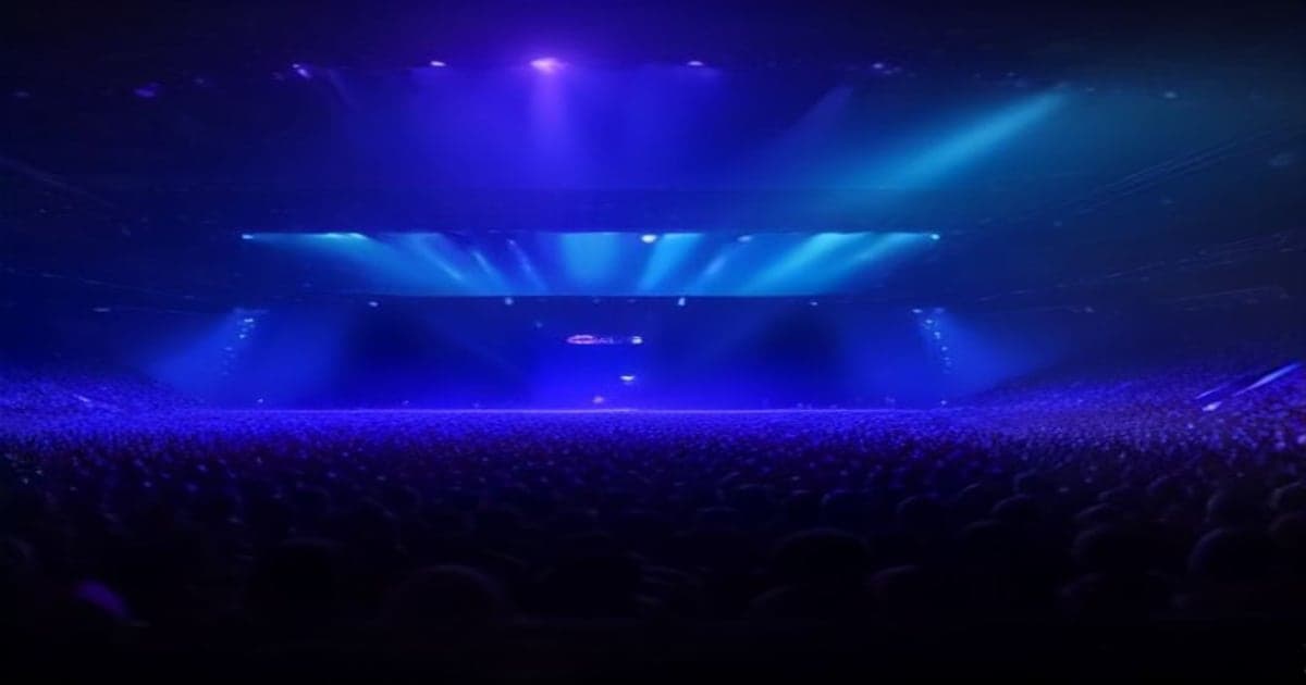 A modern, high-tech esports stage illuminated in vibrant blue and purple lights with large screens showing tournament action and a focused crowd in the background.