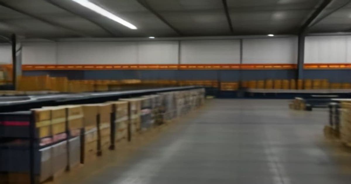 A modern automated fulfillment facility featuring conveyor belts, digital inventory dashboards, and workers overseeing robotic picking systems.